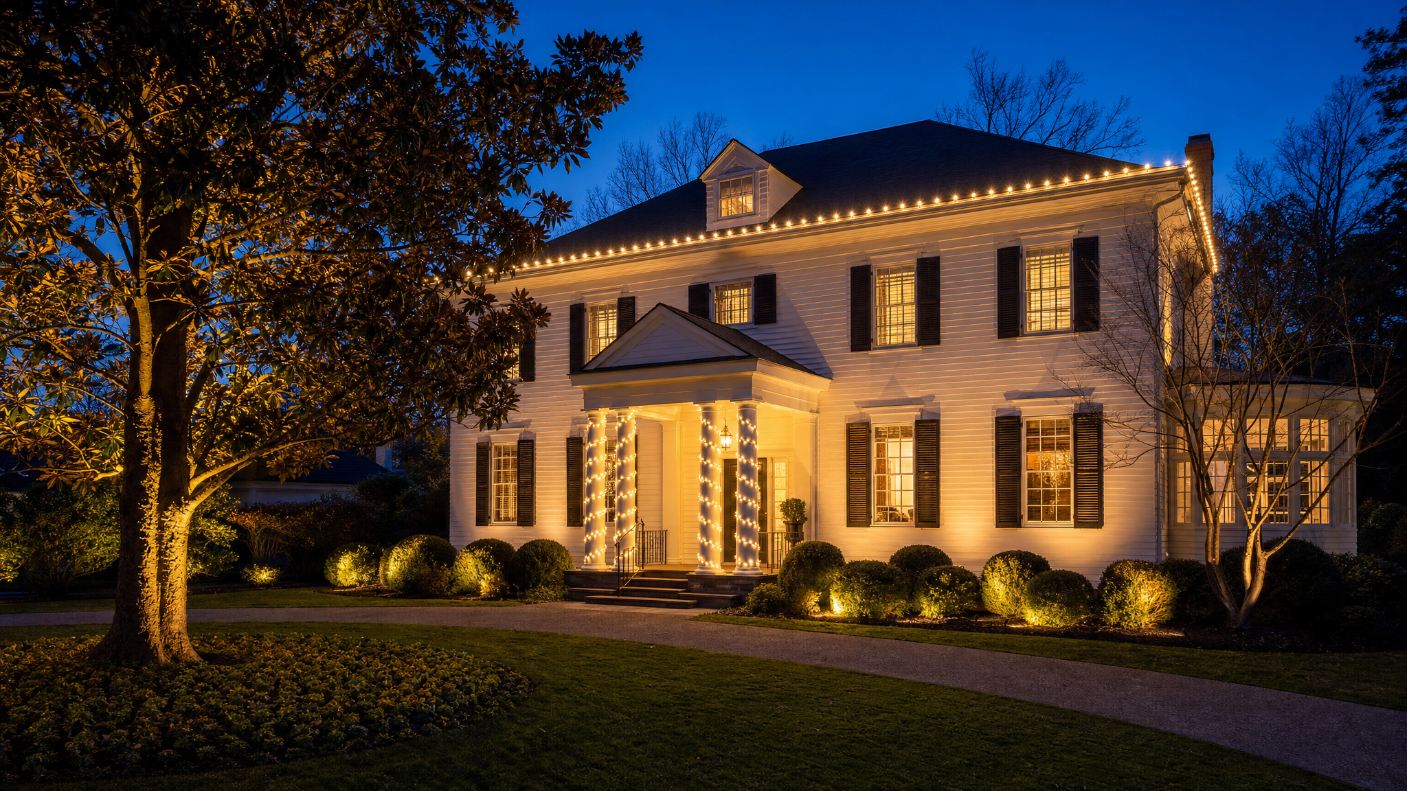 Historic Virginia colonial home with warm holiday roofline lighting at twilight